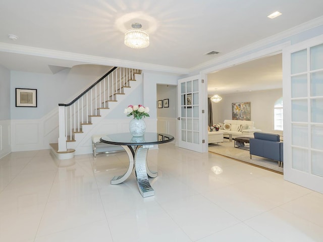 70 Scudders Ln, Roslyn Harbor, NY 11576 - tiled foyer entrance featuring french doors, crown molding, stairway, a chandelier, and wainscoting