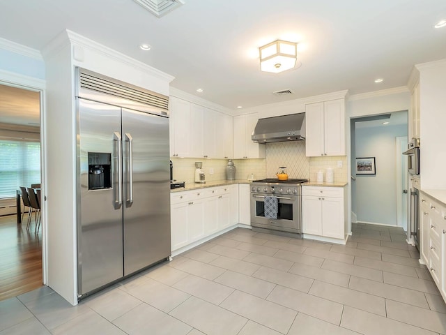 70 Scudders Ln, Roslyn Harbor, NY 11576 - kitchen featuring high end appliances, wall chimney exhaust hood, backsplash, white cabinetry, and ornamental molding