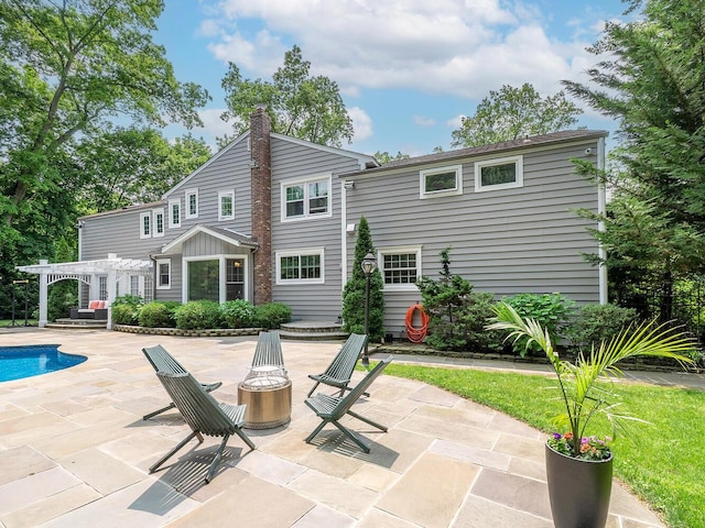 70 Scudders Ln, Roslyn Harbor, NY 11576 - rear view of house featuring a pergola, a patio, a chimney, and an outdoor pool