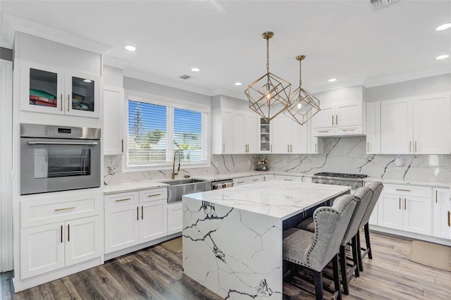7 Wendell St, Plainview, NY 11803 - kitchen with stainless steel appliances, a sink, a kitchen island, white cabinets, and ornamental molding