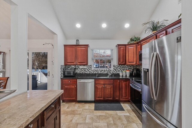 69 Plum St, Central Islip, NY 11722 - kitchen featuring appliances with stainless steel finishes, lofted ceiling, a sink, decorative backsplash, and dark countertops