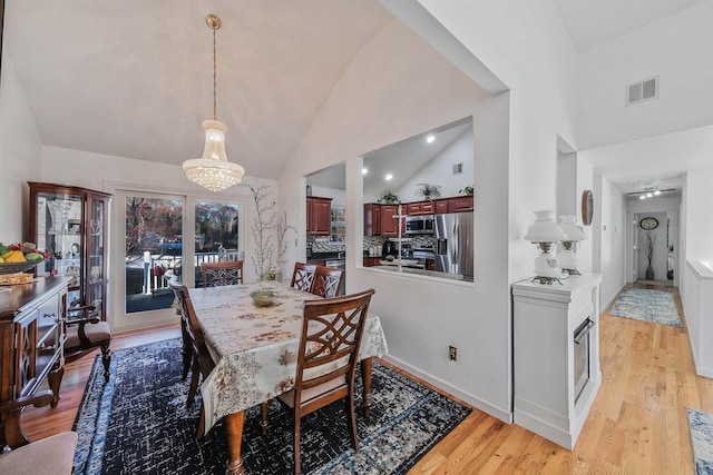 69 Plum St, Central Islip, NY 11722 - dining area with a chandelier, light wood-style floors, and high vaulted ceiling