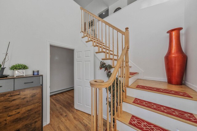 69 Plum St, Central Islip, NY 11722 - stairway with a baseboard heating unit, wood finished floors, and a high ceiling