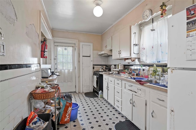 109 Leverich St, Hempstead, NY 11550 - kitchen with freestanding refrigerator, gas stove, under cabinet range hood, ornamental molding, and light floors