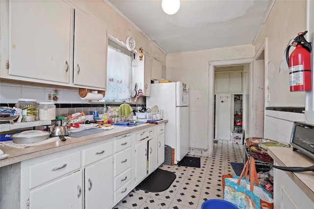 109 Leverich St, Hempstead, NY 11550 - kitchen with freestanding refrigerator, light countertops, white cabinets, light flooring, and ornamental molding