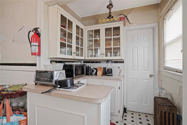 109 Leverich St, Hempstead, NY 11550 - kitchen featuring radiator, white cabinets, light countertops, glass insert cabinets, and stainless steel microwave