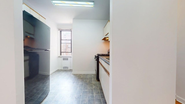 66-15 Wetherole St Unit E16, Rego Park, NY 11374 - kitchen with freestanding refrigerator, radiator, range with gas stovetop, white cabinets, and under cabinet range hood