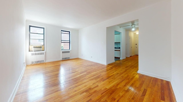 66-15 Wetherole St Unit E16, Rego Park, NY 11374 - unfurnished room with radiator heating unit, light wood-style flooring, a ceiling fan, and cooling unit