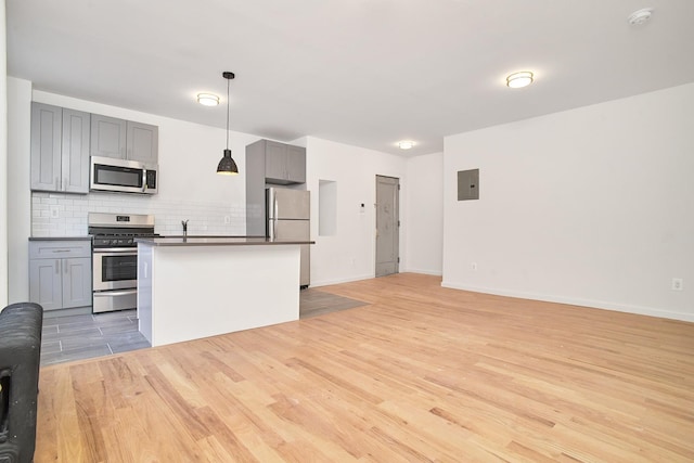 1069 Grant Ave, Bronx, NY 10456 - kitchen featuring stainless steel appliances, gray cabinetry, open floor plan, light wood-style flooring, and tasteful backsplash