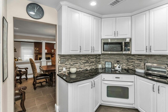 147 The Knl, Syosset, NY 11791 - kitchen with white oven, stainless steel microwave, dark countertops, dark tile patterned flooring, and crown molding
