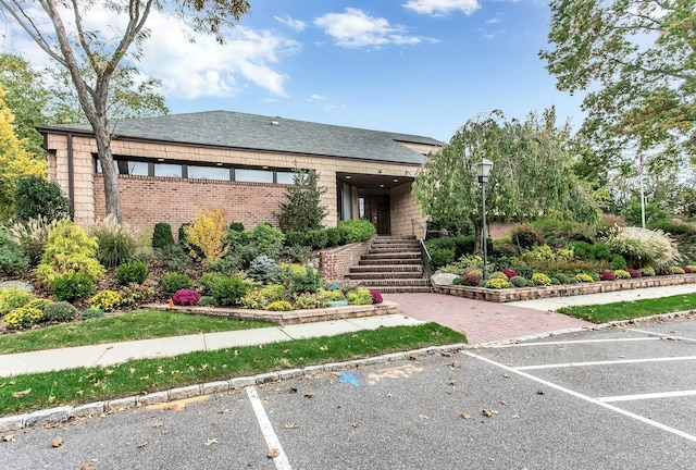 147 The Knl, Syosset, NY 11791 - view of front of home with uncovered parking, stairs, a shingled roof, and brick siding