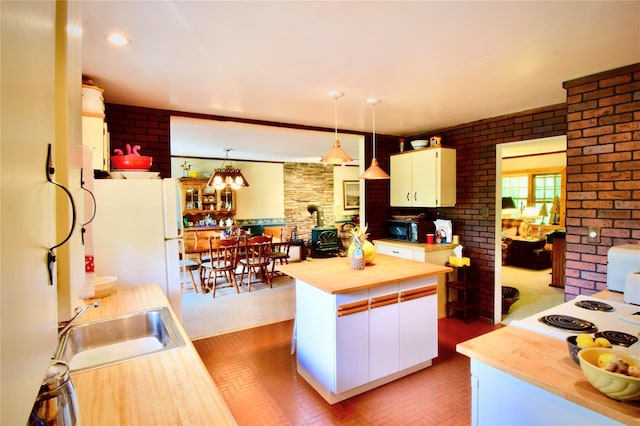 240 Trout Brook Rd, Roscoe, NY 12736 - kitchen featuring butcher block countertops, brick patterned floors, a wood stove, white cabinets, and brick wall