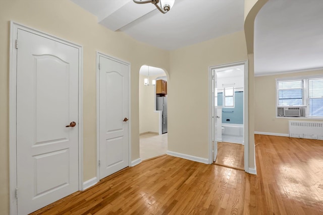 6360 102nd St Unit D8, Rego Park, NY 11374 - unfurnished bedroom with radiator, arched walkways, light wood finished floors, freestanding refrigerator, and cooling unit