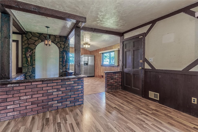 168 Gibbs Rd, Central Islip, NY 11722 - kitchen with stainless steel fridge with ice dispenser, wood finished floors, a textured ceiling, wooden walls, and open floor plan