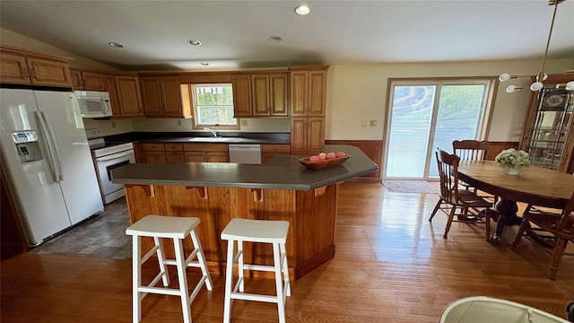 105 White Sulphur Rd, Swan Lake, NY 12783 - kitchen featuring white appliances, a wainscoted wall, dark wood-style flooring, a breakfast bar area, and dark countertops