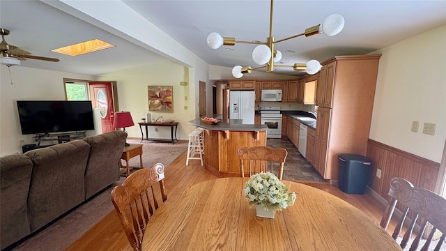 105 White Sulphur Rd, Swan Lake, NY 12783 - dining space with light wood finished floors, a ceiling fan, and a wainscoted wall