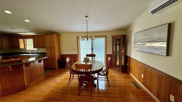 105 White Sulphur Rd, Swan Lake, NY 12783 - dining space with a wainscoted wall, a wall mounted air conditioner, light wood-type flooring, wooden walls, and a chandelier