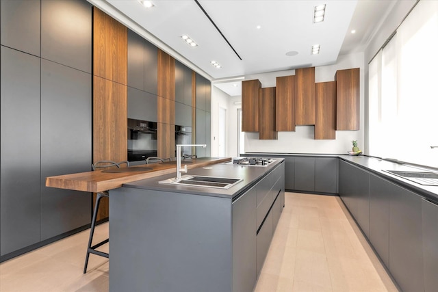 1555 Stevenson Rd, Hewlett, NY 11557 - kitchen featuring modern cabinets, a breakfast bar, a kitchen island, gray cabinets, and stainless steel gas stovetop