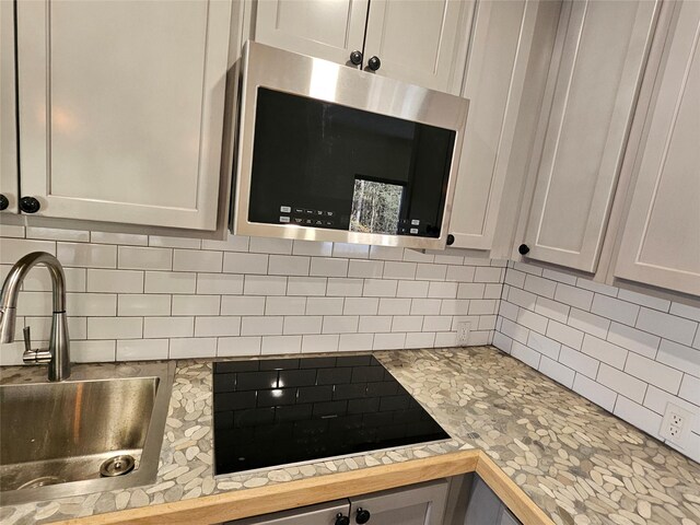 470 Shaver Hill Rd, Andes, NY 13731 - kitchen view of stainless steel microwave, a sink, black electric cooktop, backsplash, and light countertops