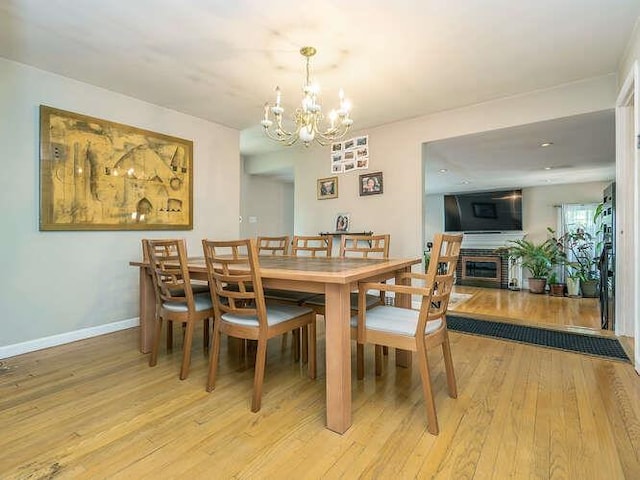 44 Glenwood Rd, Glen Head, NY 11545 - dining room with light wood-style floors, a fireplace, a chandelier, and baseboards