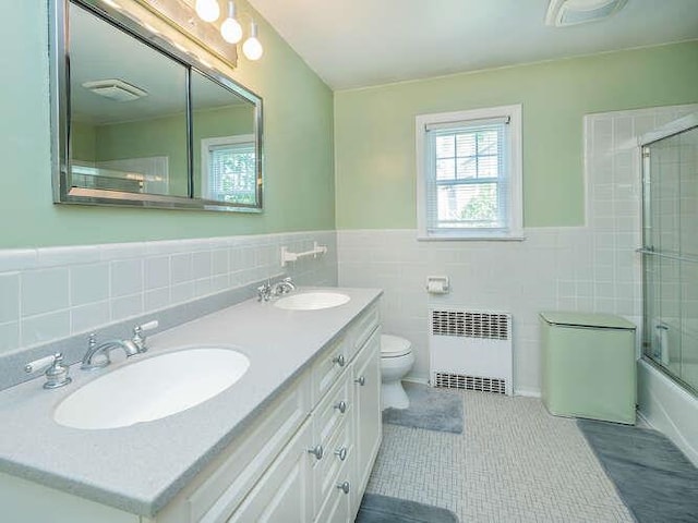 44 Glenwood Rd, Glen Head, NY 11545 - bathroom with radiator, tile walls, double vanity, toilet, and tile patterned floors