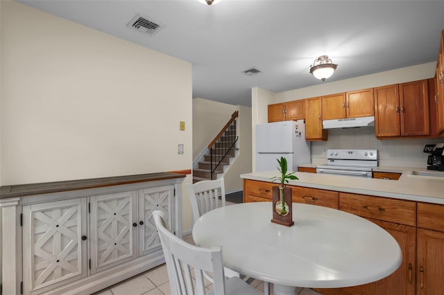 14 Bleakley Dr Unit 14, Peekskill, NY 10566 - kitchen with white appliances, under cabinet range hood, light countertops, brown cabinets, and light tile patterned floors