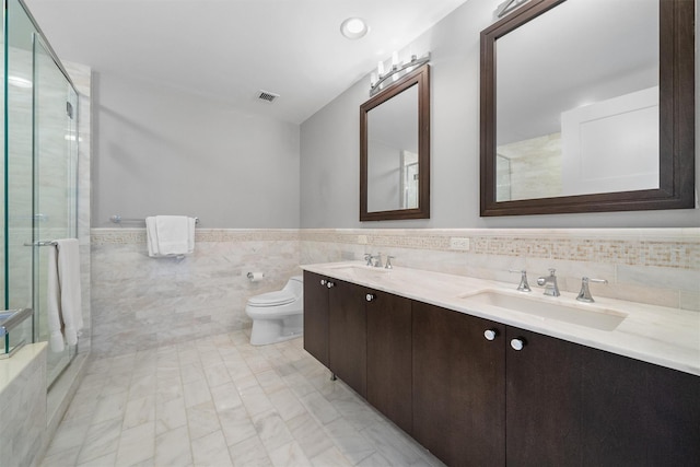 5 Renaissance Sq Unit 23B, White Plains, NY 10601 - bathroom with tile walls, double vanity, toilet, a shower stall, and wainscoting
