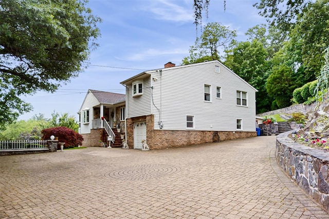 81 Avondale Rd, Yonkers, NY 10710 - view of home's exterior with a chimney, brick siding, and decorative driveway