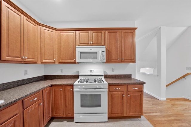 28 Winhaven Ct Unit 20, Highland Falls, NY 10928 - kitchen with white appliances, dark countertops, brown cabinets, and light wood-style floors