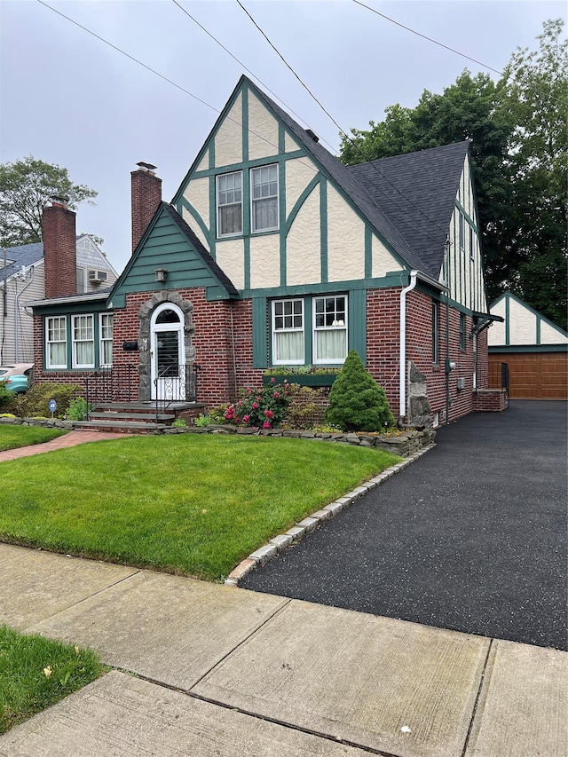 8 Alexine Ave, East Rockaway, NY 11518 - english style home with brick siding, a chimney, a front yard, an outdoor structure, and a detached garage
