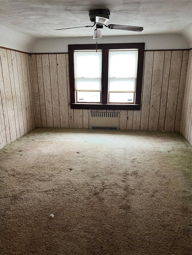 8 Alexine Ave, East Rockaway, NY 11518 - empty room with radiator heating unit, carpet flooring, a ceiling fan, wood walls, and lofted ceiling