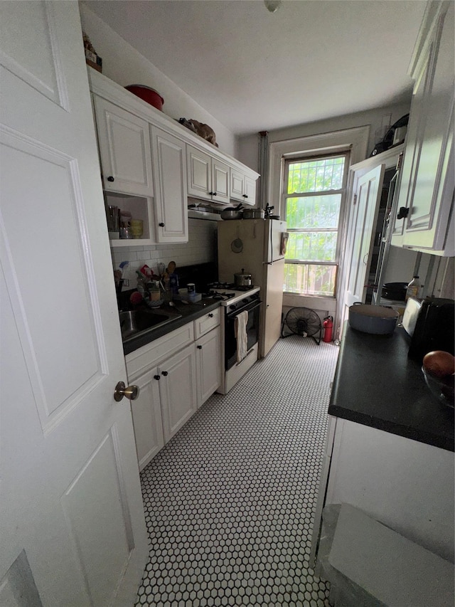 21 Jefferson St, Brooklyn, NY 11206 - kitchen featuring range with gas cooktop, white cabinets, dark countertops, and decorative backsplash