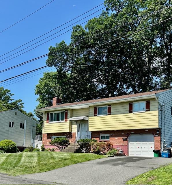 25 Waldron Dr, Stony Point, NY 10980 - raised ranch featuring brick siding, a chimney, a front lawn, and a garage