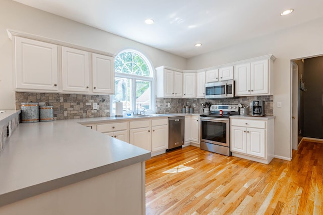 44 Croft Ln, Smithtown, NY 11787 - kitchen featuring appliances with stainless steel finishes, backsplash, light wood-type flooring, white cabinets, and recessed lighting