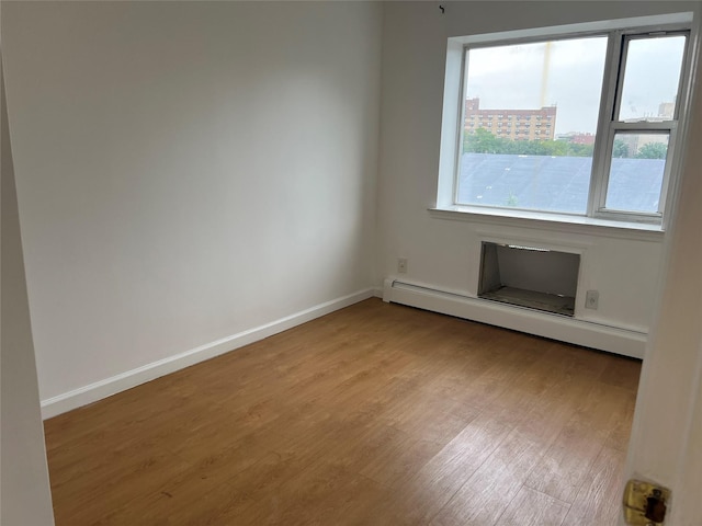 55-05 98th St, Corona, NY 11368 - spare room with wood finished floors and a baseboard heating unit