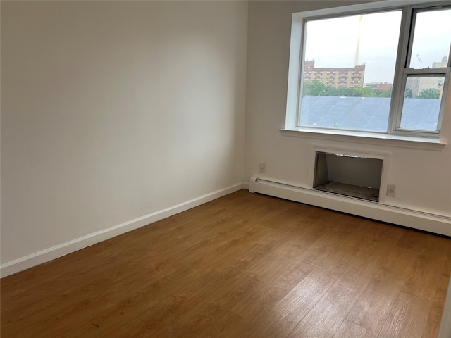 55-05 98th St, Corona, NY 11368 - unfurnished room featuring wood finished floors and a baseboard radiator