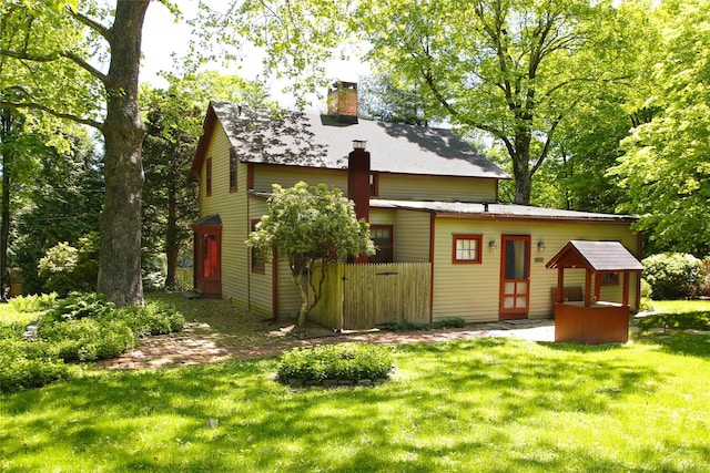 rear view of property with a chimney and a yard