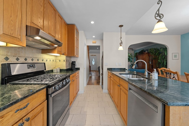 78-32 76th St, Glendale, NY 11385 - kitchen featuring stainless steel appliances, under cabinet range hood, a sink, arched walkways, and a peninsula