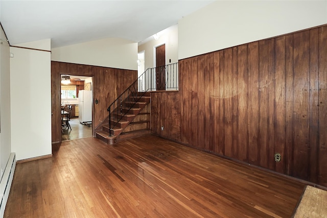6 Pequot Ave, Port Washington, NY 11050 - unfurnished living room featuring wood-type flooring, a baseboard radiator, stairway, and vaulted ceiling