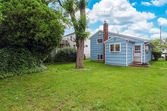 6 Pequot Ave, Port Washington, NY 11050 - back of house featuring entry steps, a lawn, and a chimney
