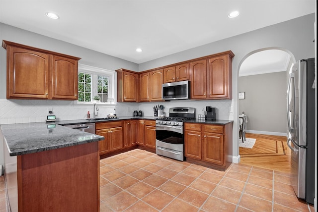 2 SE Ct, Wallkill, NY 12589 - kitchen with appliances with stainless steel finishes, arched walkways, a peninsula, tasteful backsplash, and brown cabinets