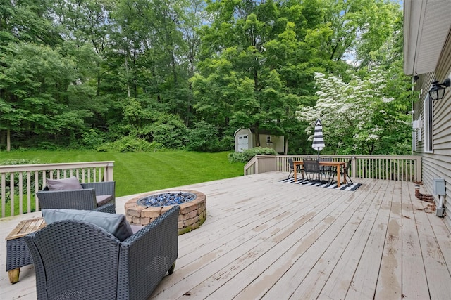 2 SE Ct, Wallkill, NY 12589 - deck featuring outdoor dining area, a fire pit, a storage unit, a lawn, and view of wooded area