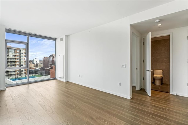 133-36 37th Ave Unit 11H, Flushing, NY 11354 - unfurnished room featuring wood finished floors, a wall of windows, and a view of city
