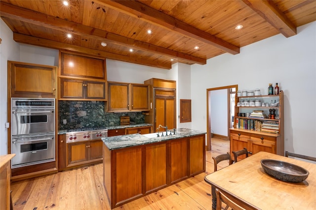 215 Hillcrest Dr N, Orient, NY 11957 - kitchen featuring stainless steel appliances, tasteful backsplash, light wood finished floors, brown cabinets, and a wooden ceiling with exposed beams