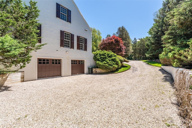 215 Hillcrest Dr N, Orient, NY 11957 - view of property exterior with gravel driveway, an attached garage, and stucco siding