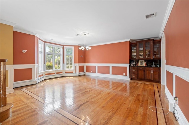 135 Millet St N, Dix Hills, NY 11746 - unfurnished living room featuring a chandelier, light wood-type flooring, ornamental molding, a wainscoted wall, and a decorative wall