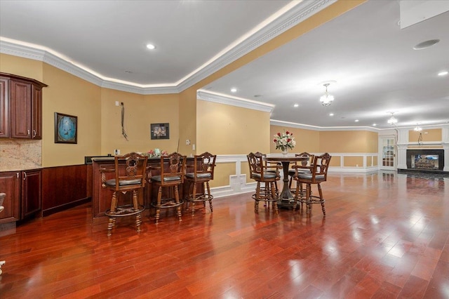 135 Millet St N, Dix Hills, NY 11746 - dining area featuring a wainscoted wall, ornamental molding, bar area, a decorative wall, and wood finished floors