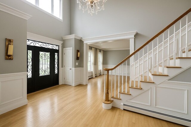 1 Ada Ln, East Setauket, NY 11733 - foyer entrance featuring baseboard heating, stairway, a chandelier, wood finished floors, and a decorative wall