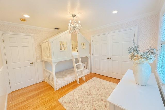 1 Ada Ln, East Setauket, NY 11733 - bedroom with crown molding, a chandelier, light wood-style flooring, wallpapered walls, and a closet
