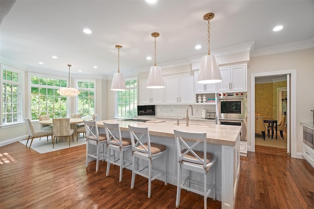 28 Stone Paddock Pl, Bedford, NY 10506 - kitchen featuring crown molding, white cabinetry, stainless steel double oven, a kitchen island with sink, and backsplash